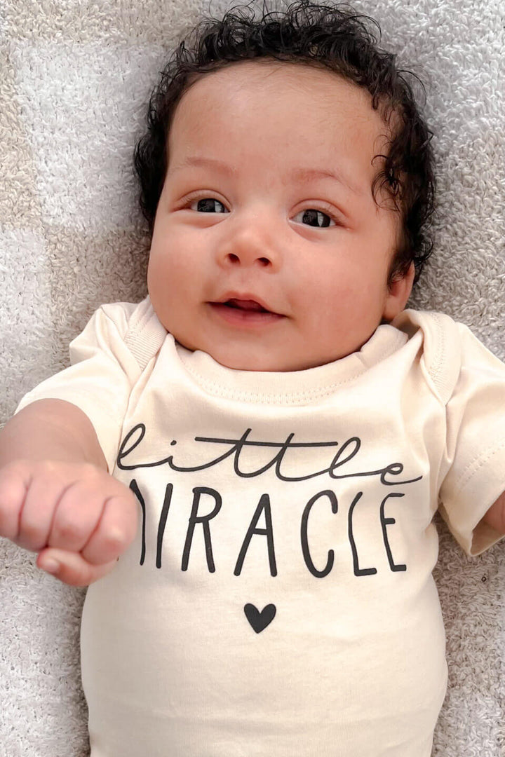 close up of little miracle graphic on natural cotton baby bodysuit for newborns