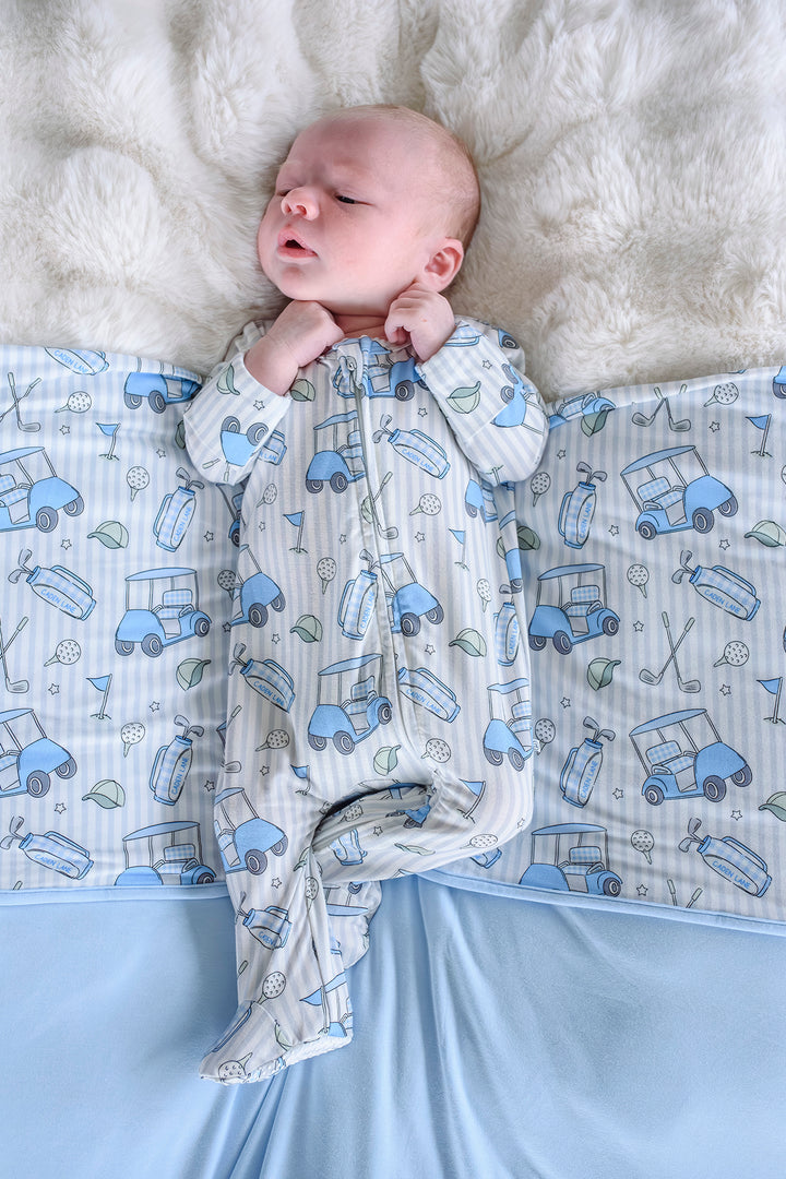 baby laying on caddie crew blue bamboo blanket in matching zipper footie