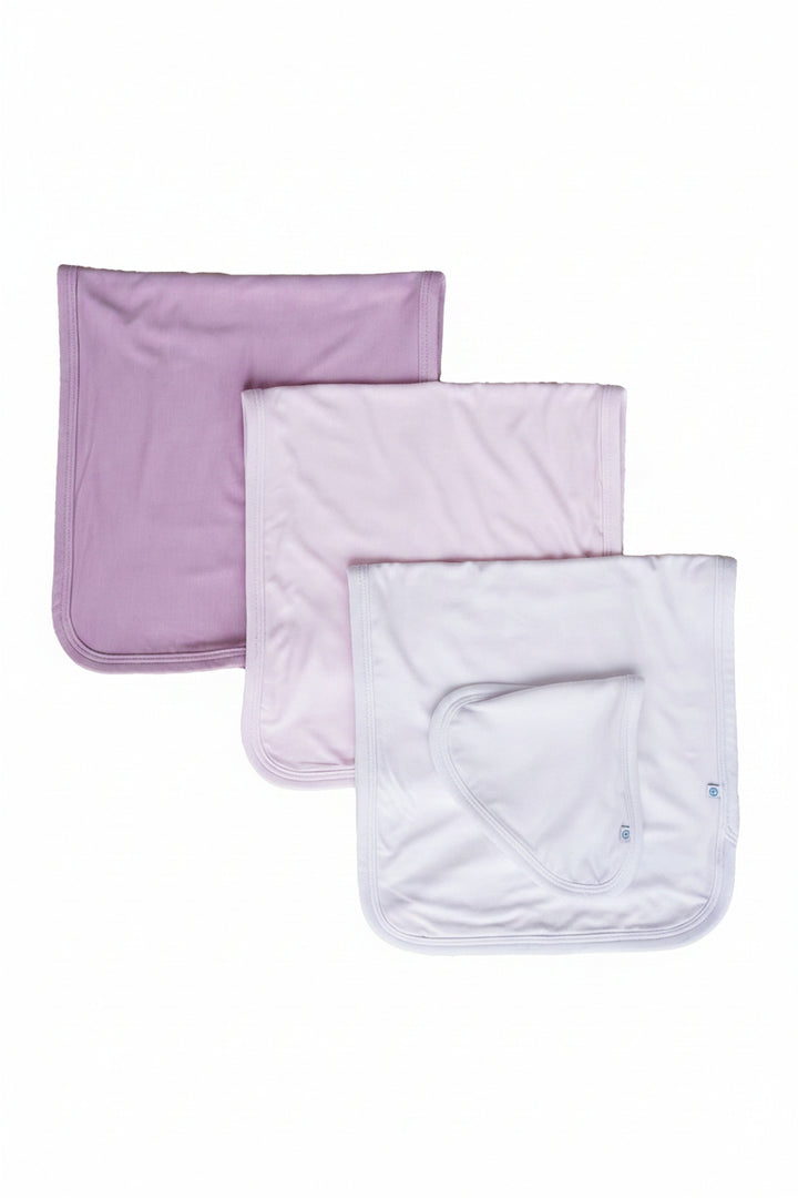 Three Caden Lane square baby bandana-style burp clothes in n soft pastel shades of purple on a plain white background.