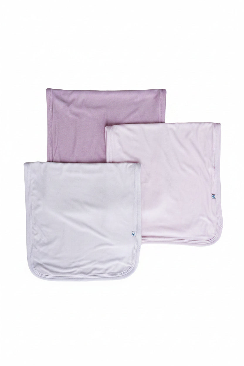 Three Caden Lane folded baby burp clothes in soft shades of purple.