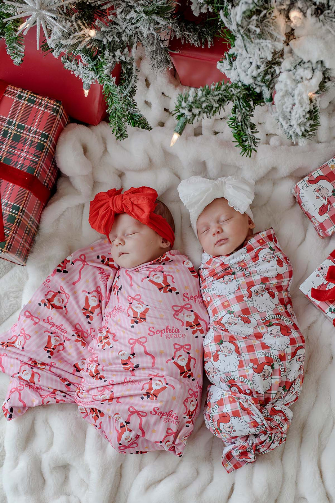 Personalized Christmas bamboo swaddle blankets in Cozy Claus and Jolly Ribbon prints featuring sleeping newborn twins, ideal for matching sibling photos and holiday baby gifts.