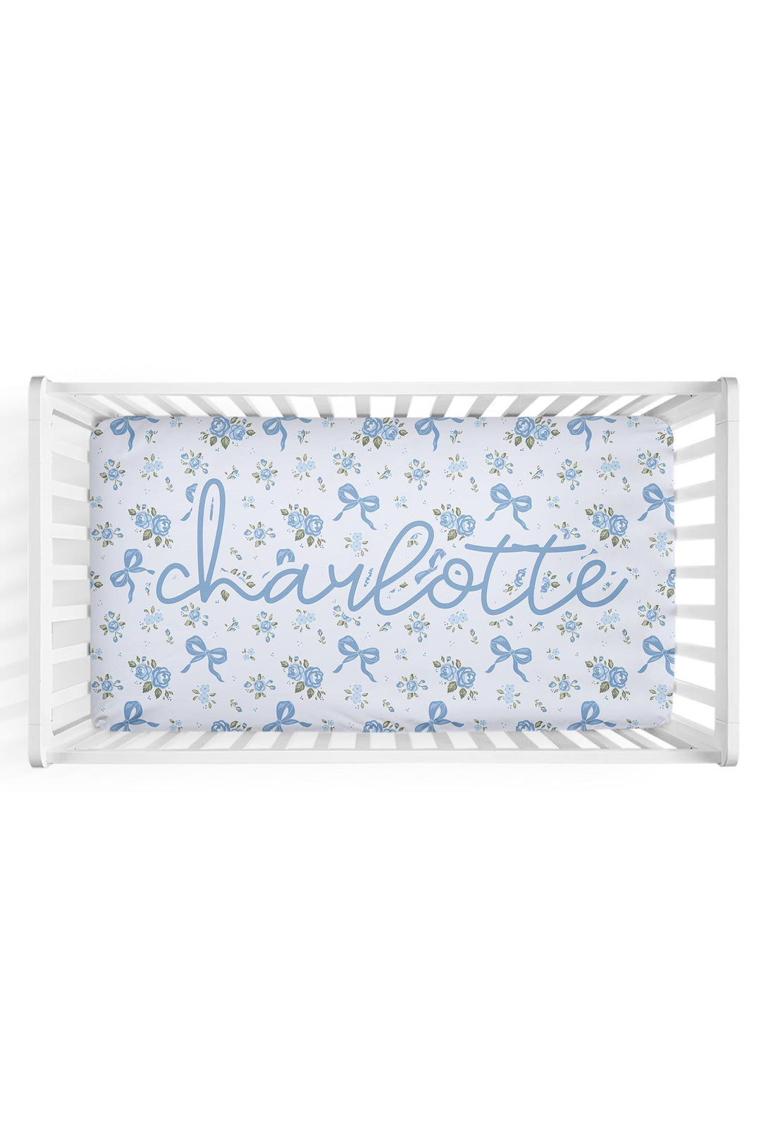 Personalized white crib sheet with blue floral and bow print, customized with the name "Charlotte" in cursive script