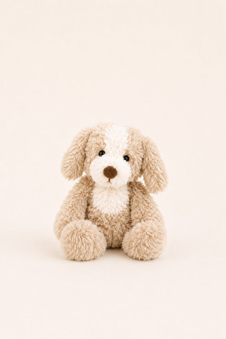 A Caden Lane plush stuffed dog toy in light beige and cream with a brown nose, sitting centered against a plain warm off-white background.