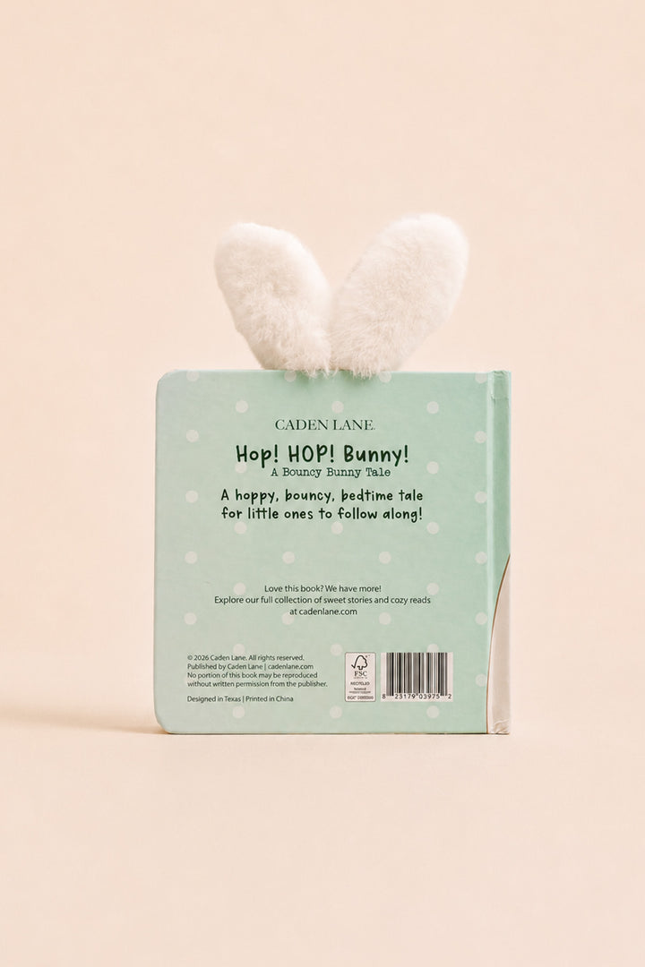 The back cover of the children's book 'Hop! Hop! Bunny!' by Cadence Lane, featuring a mint green background with white polka dots and a fluffy white bunny ear bookmark attached at the top, set against a solid pale peach background.