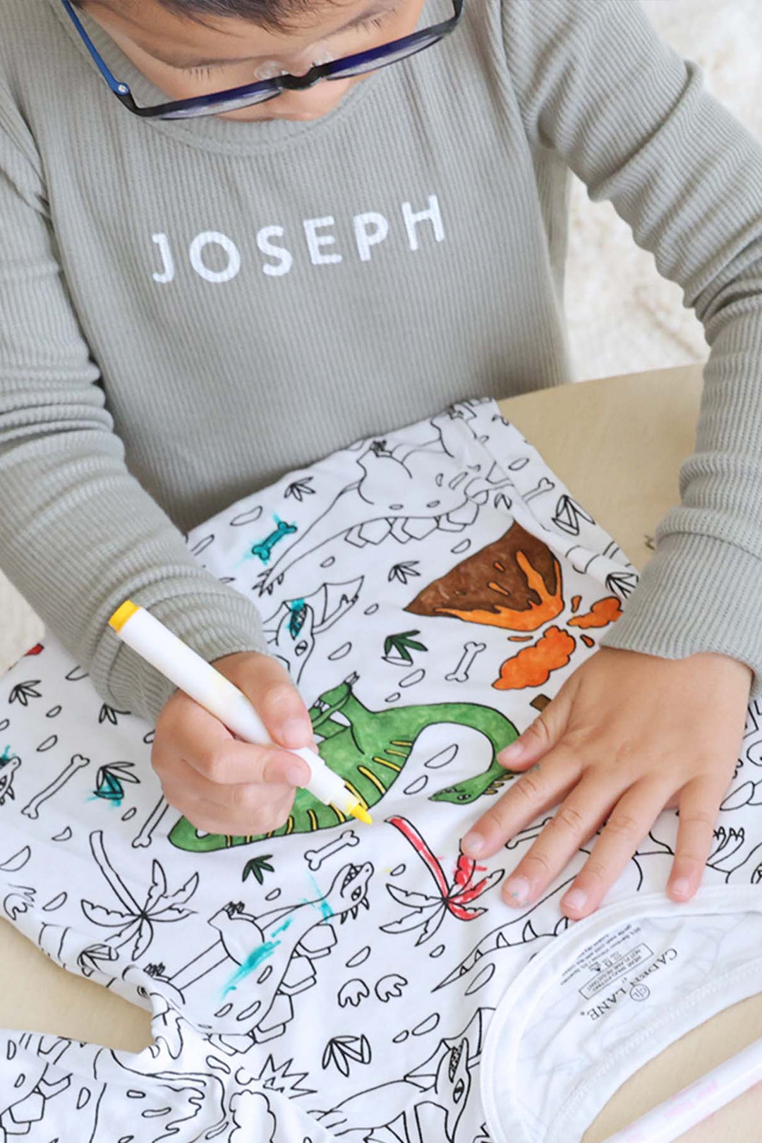 boy coloring the Jurassic Playground Colorable Pajama Two Piece Set
