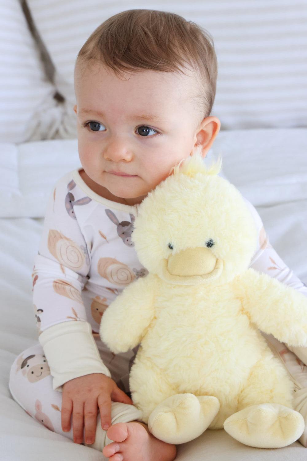 baby boy in farm pajama with yellow duck stuffed animal 