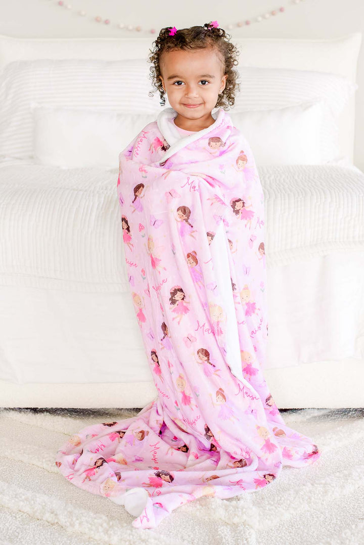 Toddler girl standing wrapped in the pink Fairy Wishes personalized kids&