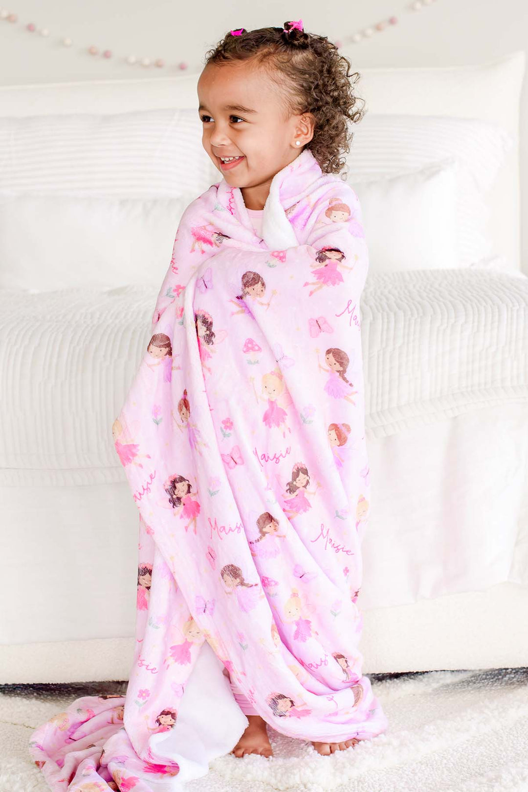 Smiling toddler girl wrapped in the pink Fairy Wishes personalized kids&