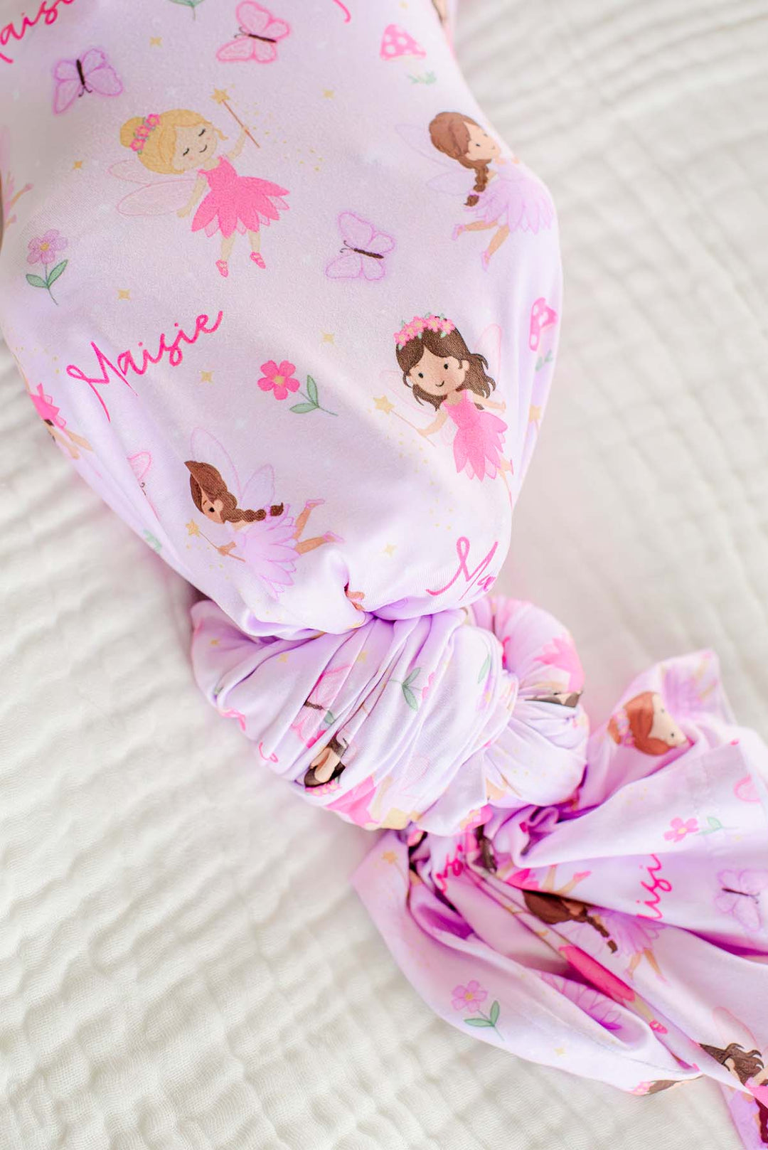 Knotted end of the pink Fairy Wishes personalized swaddle showing the fairy, butterfly and custom name print