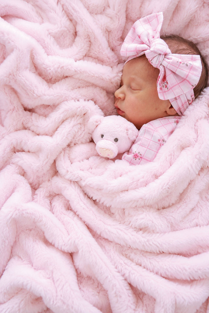 Sleeping baby with a bow headband and teddy bear, wrapped in a barely pink double-ruched faux fur blanket