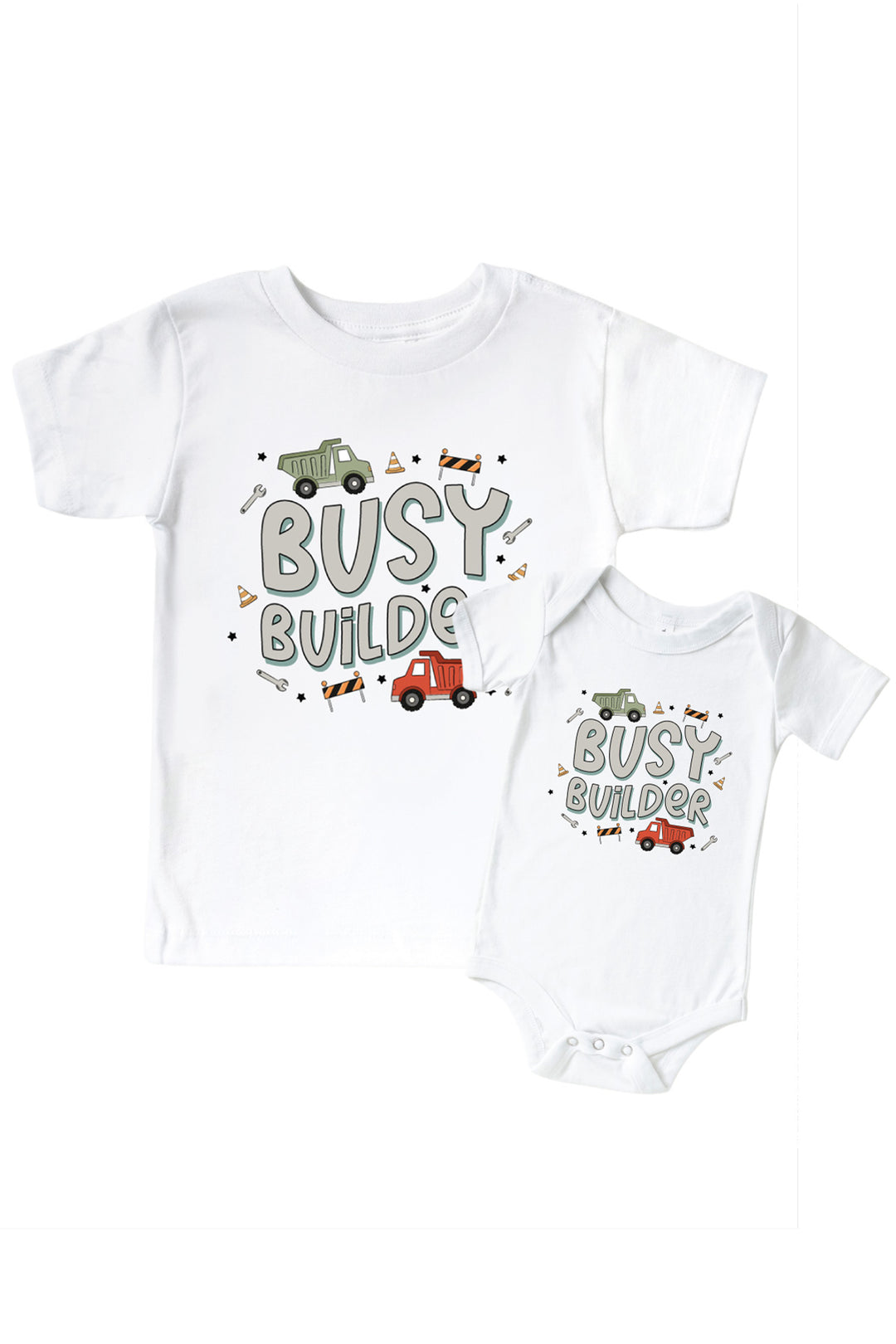 Flat lay of a Caden Lane white tee in a Busy Builder print featuring green and red dump trucks and wrenches, reading "Busy builder," paired with a matching bodysuit.