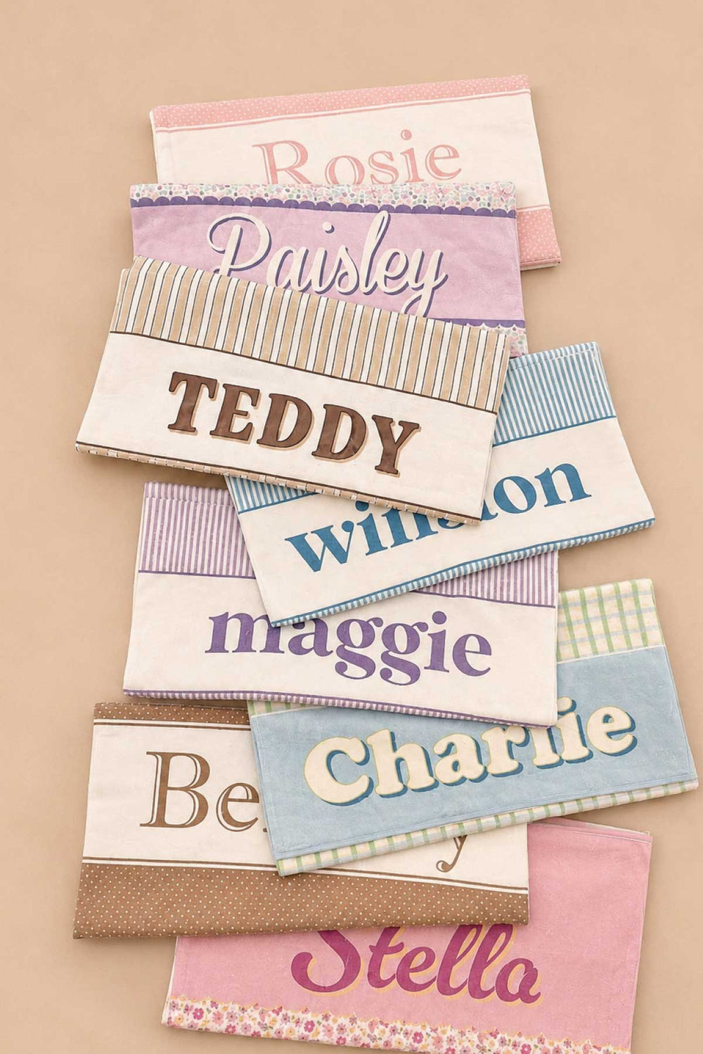 Collection of personalized pet towels in various prints and colors, fanned out to show customization options with different pet names