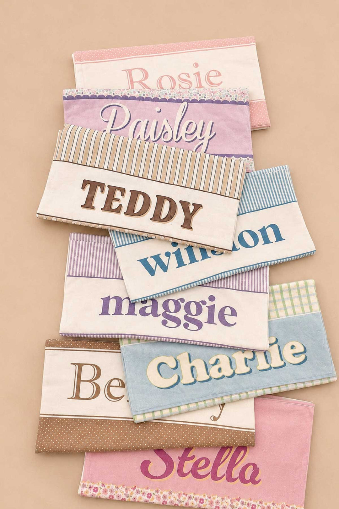 Collection of personalized pet towels in various prints and colors, fanned out to show customization options with different pet names
