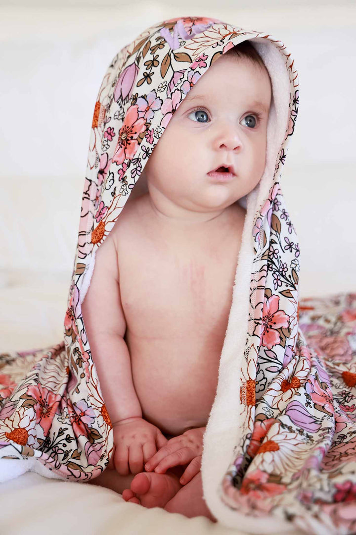 sitting baby with purple floral embroidered towel on her head