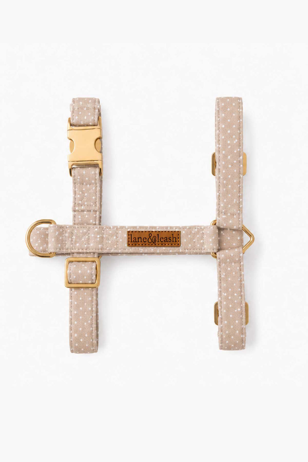 Flat lay overhead view of latte brown polka dot H-style strap dog harness showing the H-shaped design with gold hardware