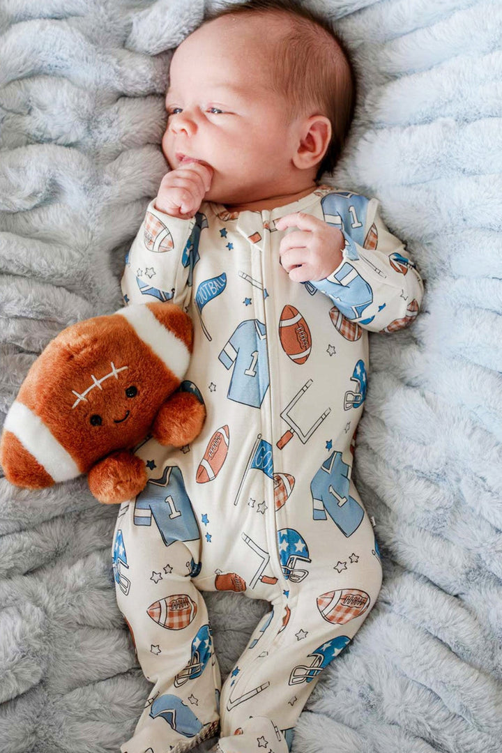 Newborn baby wearing the Caden Lane huddles & cuddles blue zip romper. The print features football prints! 