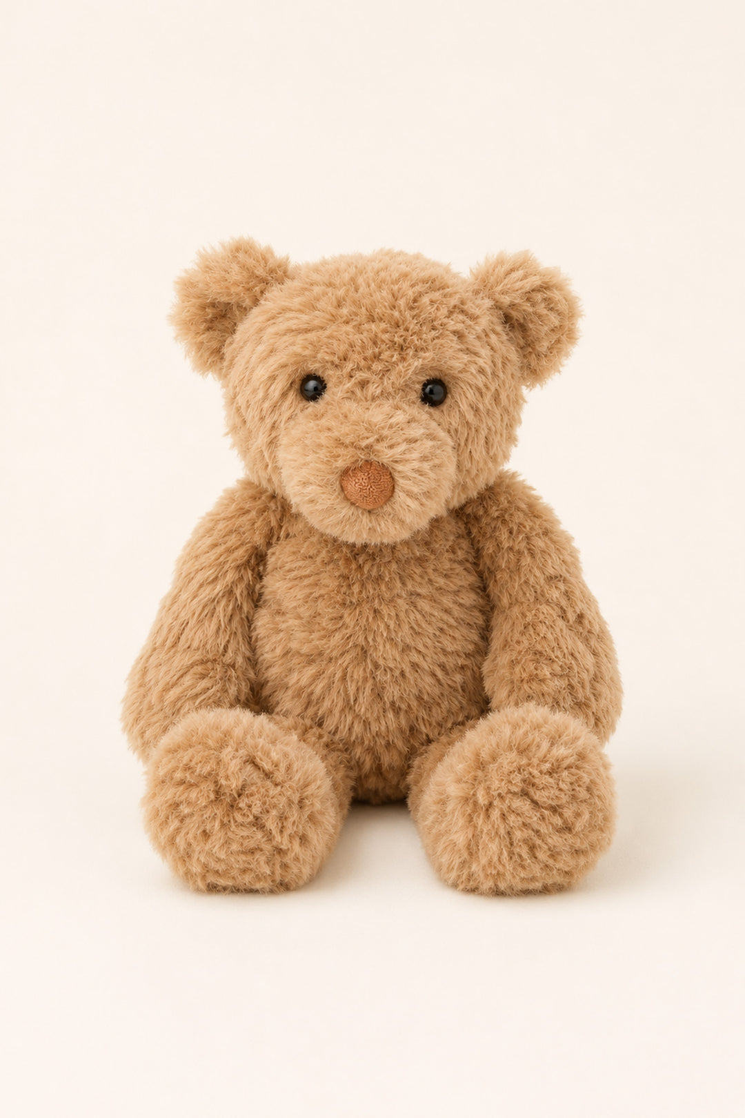 A Caden Lane plush teddy bear made of soft, curly light brown faux fur, sitting against a solid off-white background.