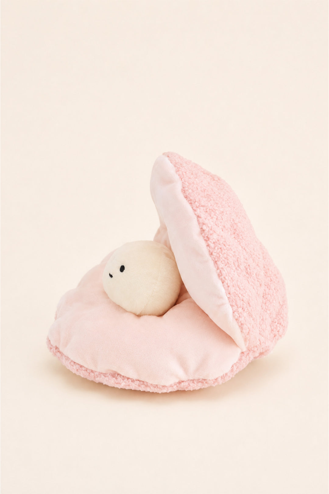 A Caden Lane cute plush toy featuring a small white bear with a black embroidered face nestled inside an open pink teddy shell, set against a solid cream background.
