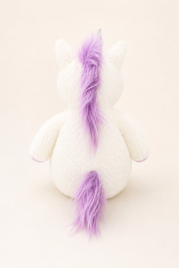 A Caden Lane white plush unicorn toy shown from the back, featuring a fluffy purple mane and tail against a solid cream background.