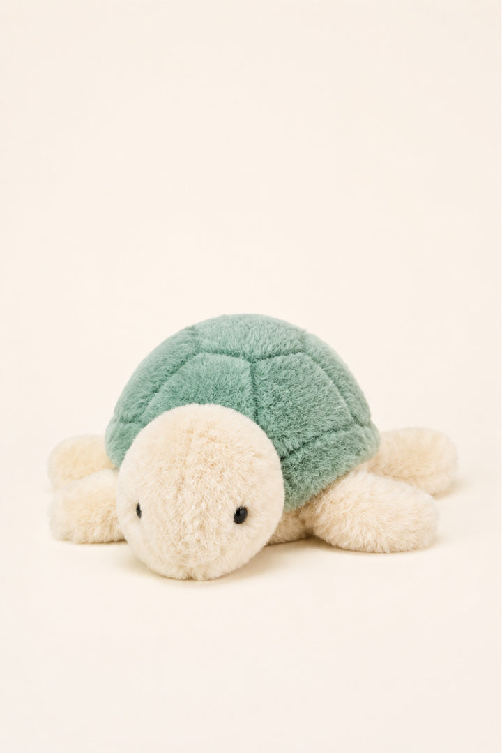 A Caden Lane plush sea turtle toy with a textured mint green shell and a soft cream-colored head, flippers, and legs, photographed on a clean, solid cream background.