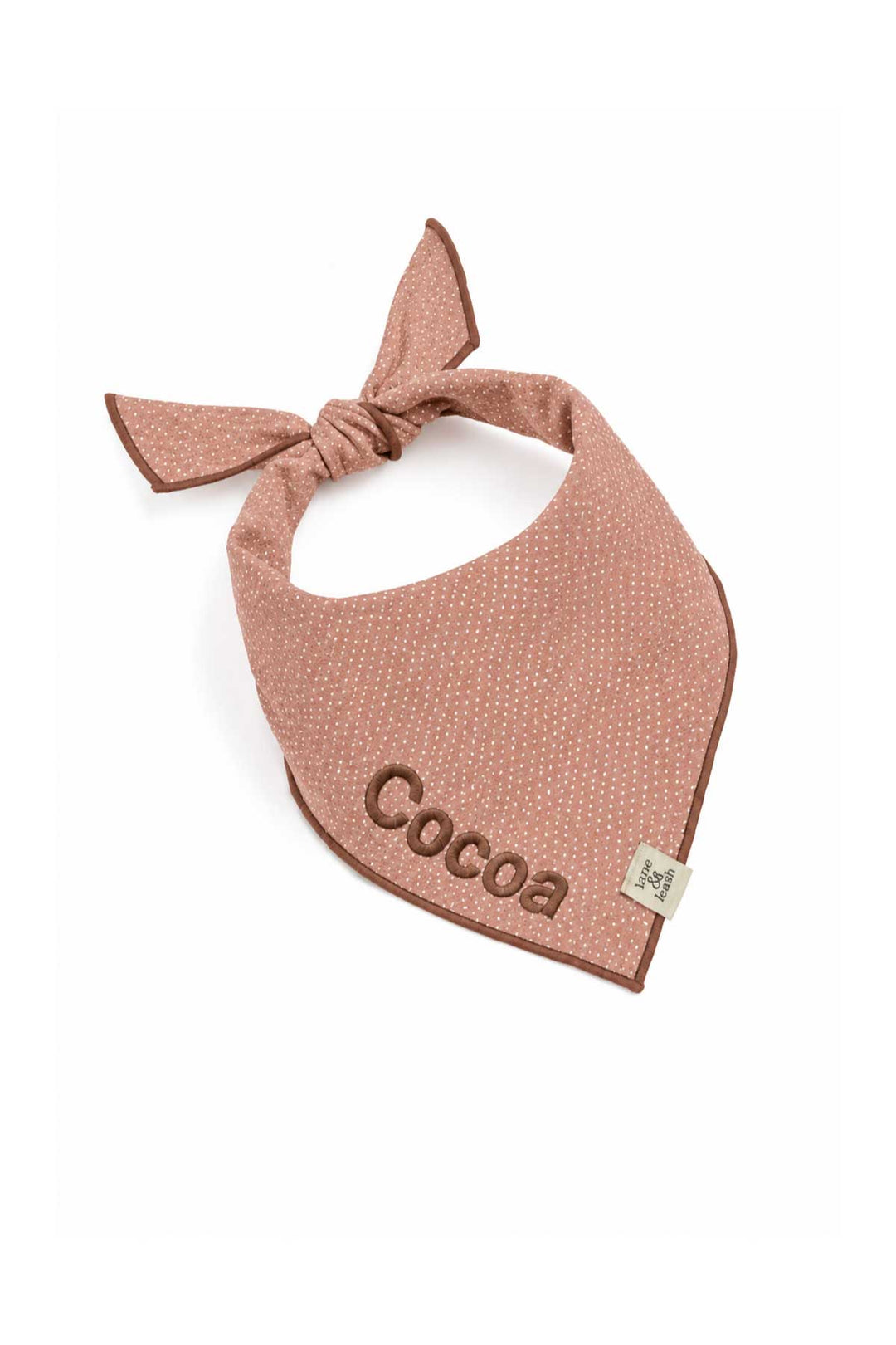 Latte pink polka dot pet bandana tied at the neck with the name 'Cocoa' embroidered in brown thread