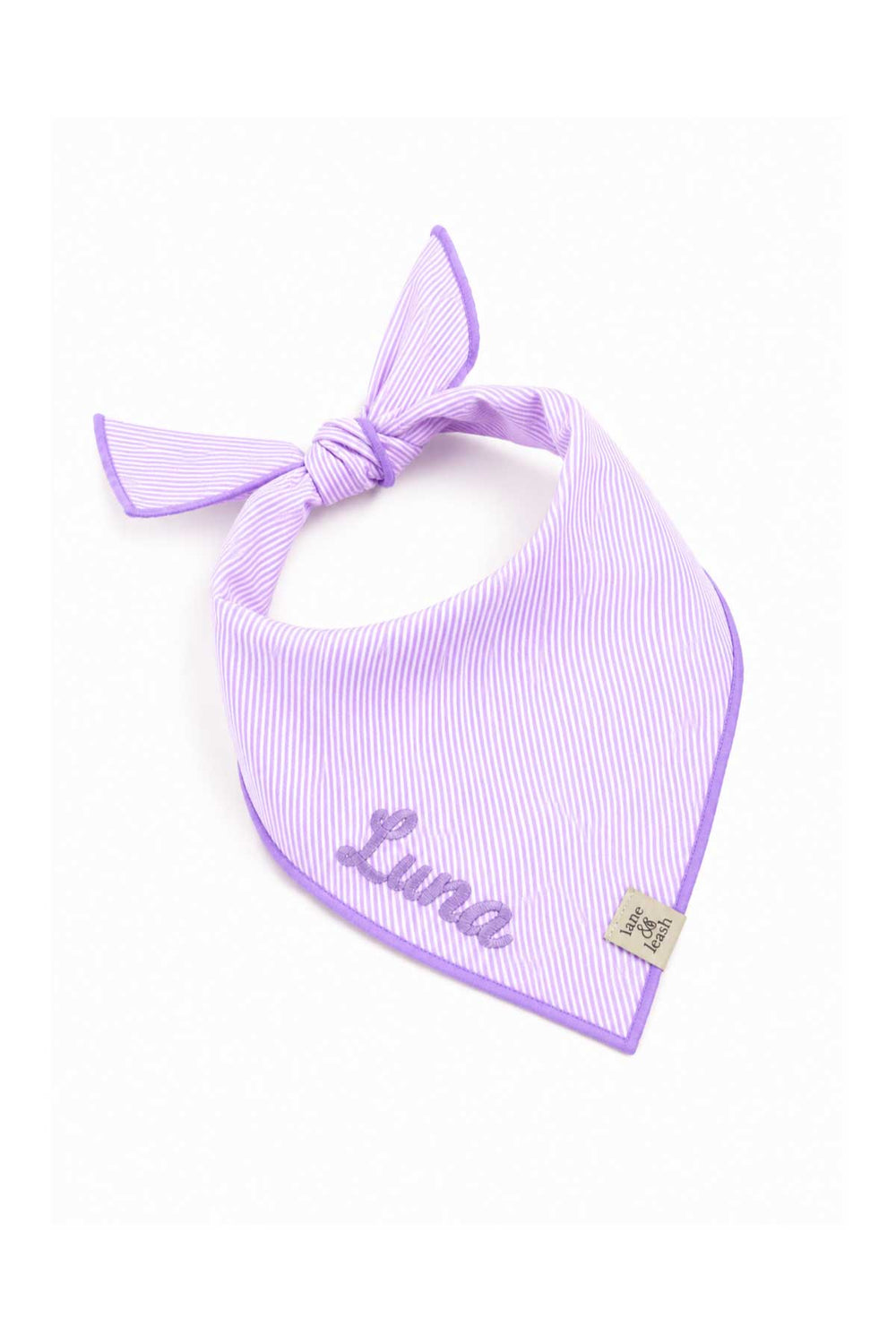 Lavender and white striped pet bandana tied in a bow knot with the name "Luna" embroidered in script, showing the tied wearing style