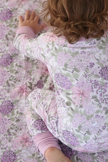 baby girl crawling on bamboo blanket in lavender lullaby print wearing matching pajama romper 