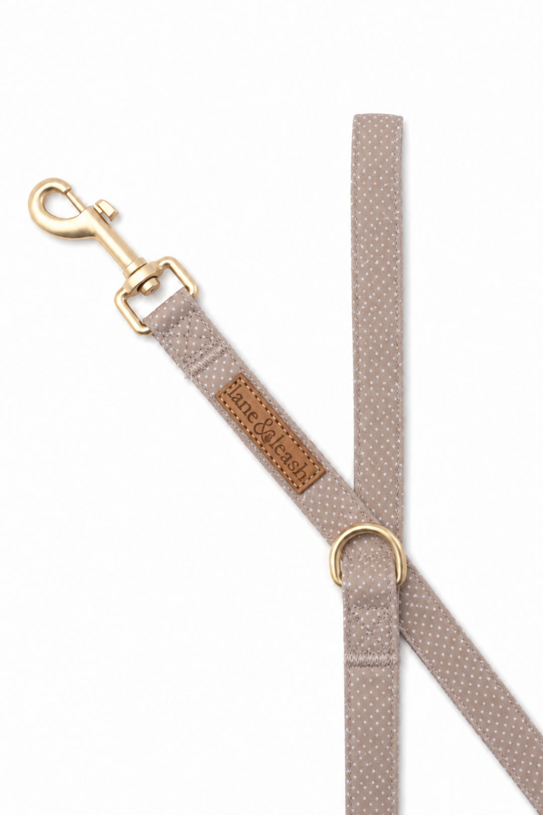 Close-up of the latte brown polka dot dog leash clasp end showing the gold swivel hook and D-ring attachment