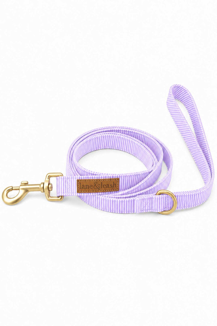 Solid lavender heavy-duty dog leash coiled on white background, featuring a gold swivel clasp and Lane and Leash leather label