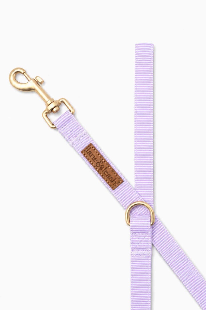 Close-up detail of the lavender dog leash showing the gold swivel clasp, Lane and Leash leather label, and D-ring hardware