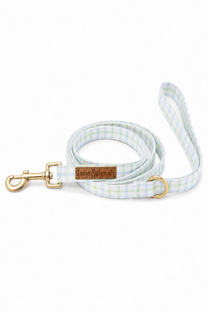 Heavy-duty dog leash in green and blue picnic plaid, coiled and showing the gold swivel clasp, D-ring, and Lane & Leash leather label