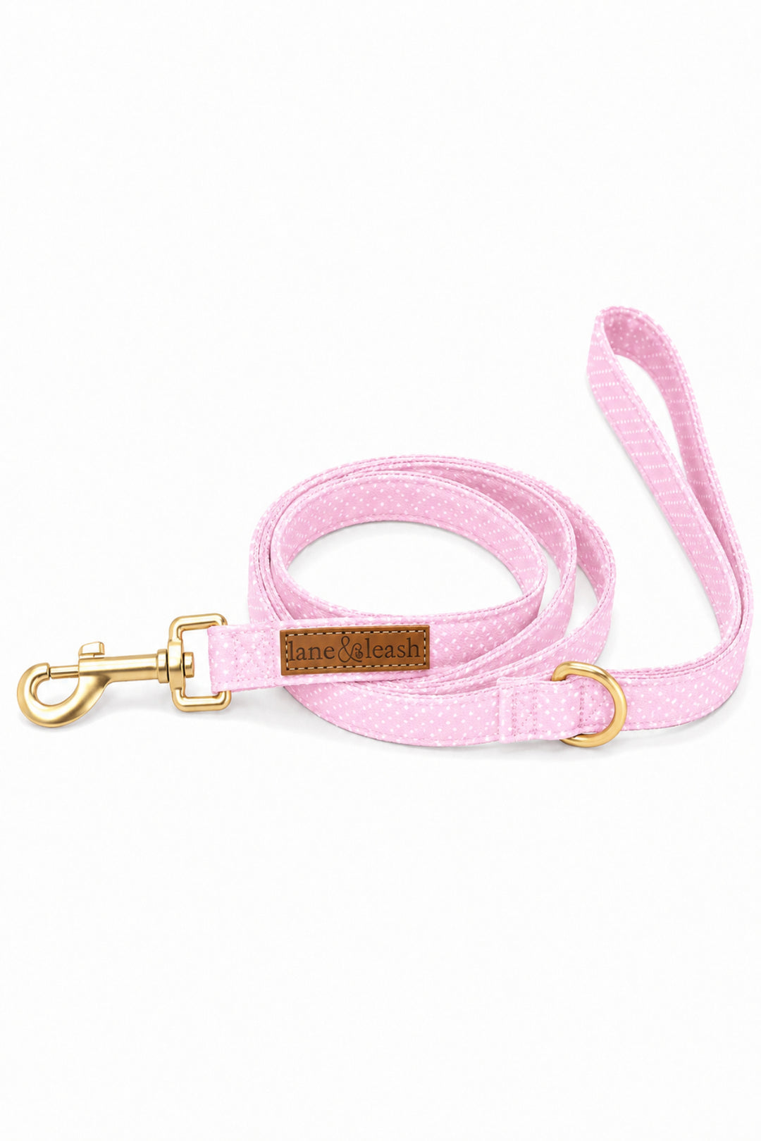 Pink polka dot heavy-duty dog leash coiled up with gold swivel clasp hook, D-ring, and leather brand label