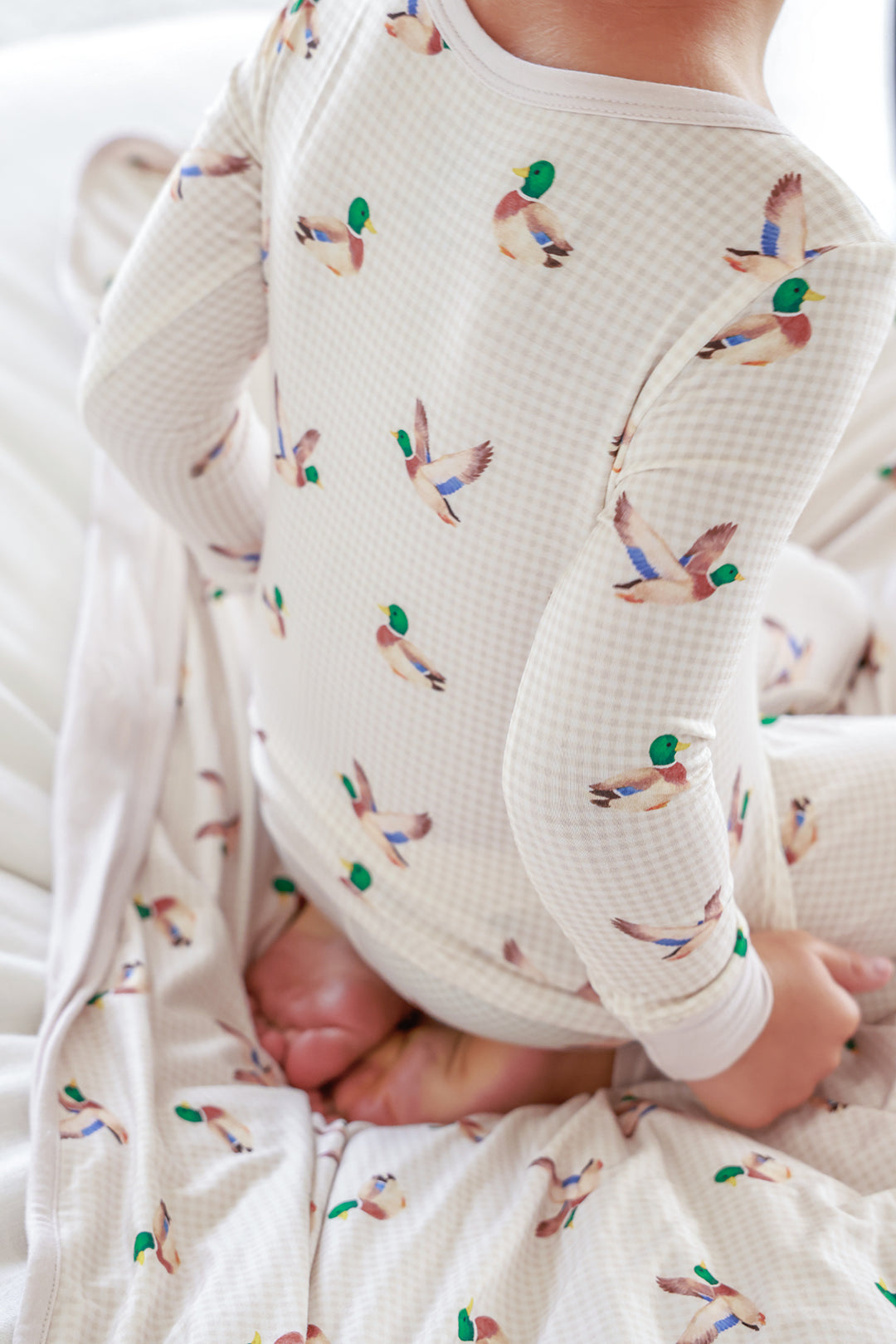 Close-up of child's torso wearing little mallard duck print bamboo pajama top showing flying duck pattern detail