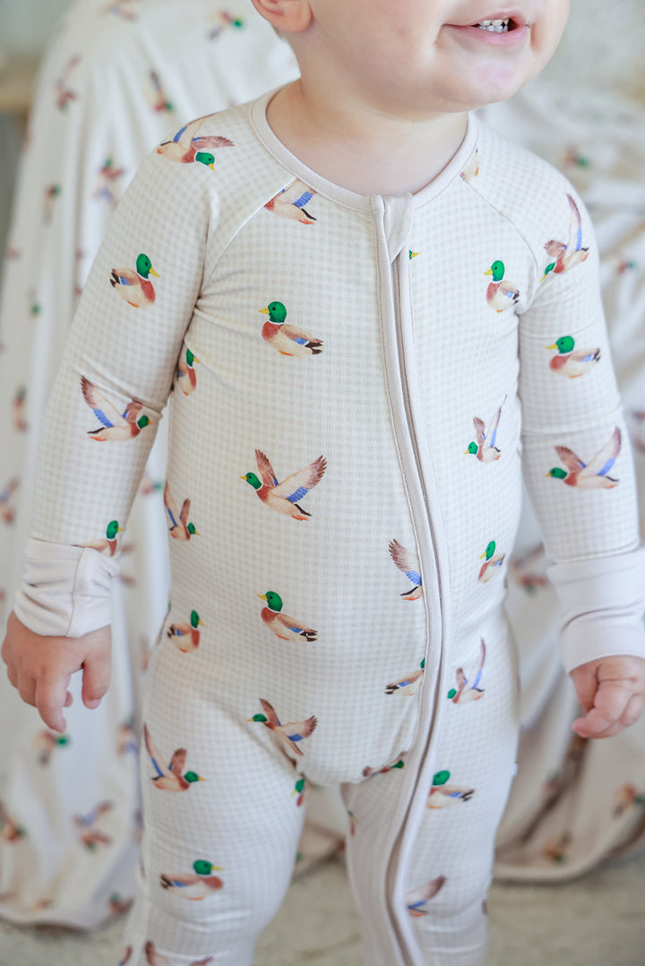 Close-up front view of toddler wearing little mallard duck print convertible zip romper showing zip and duck print detail