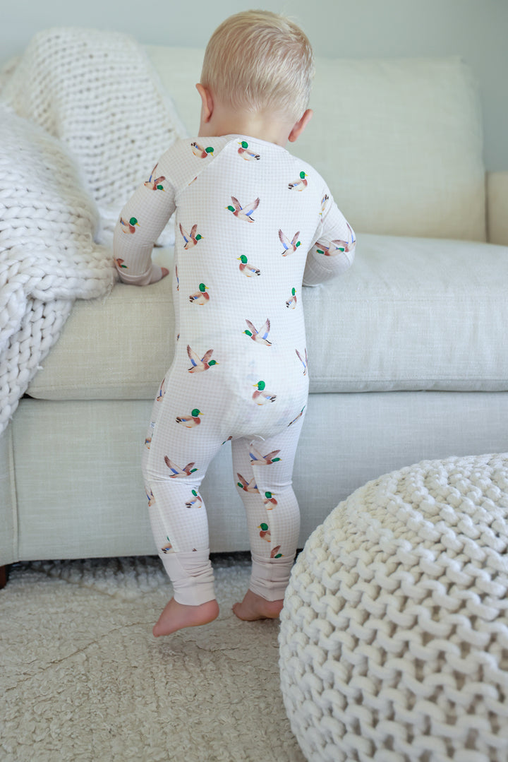 Toddler standing facing away showing the back of little mallard duck print convertible zip romper