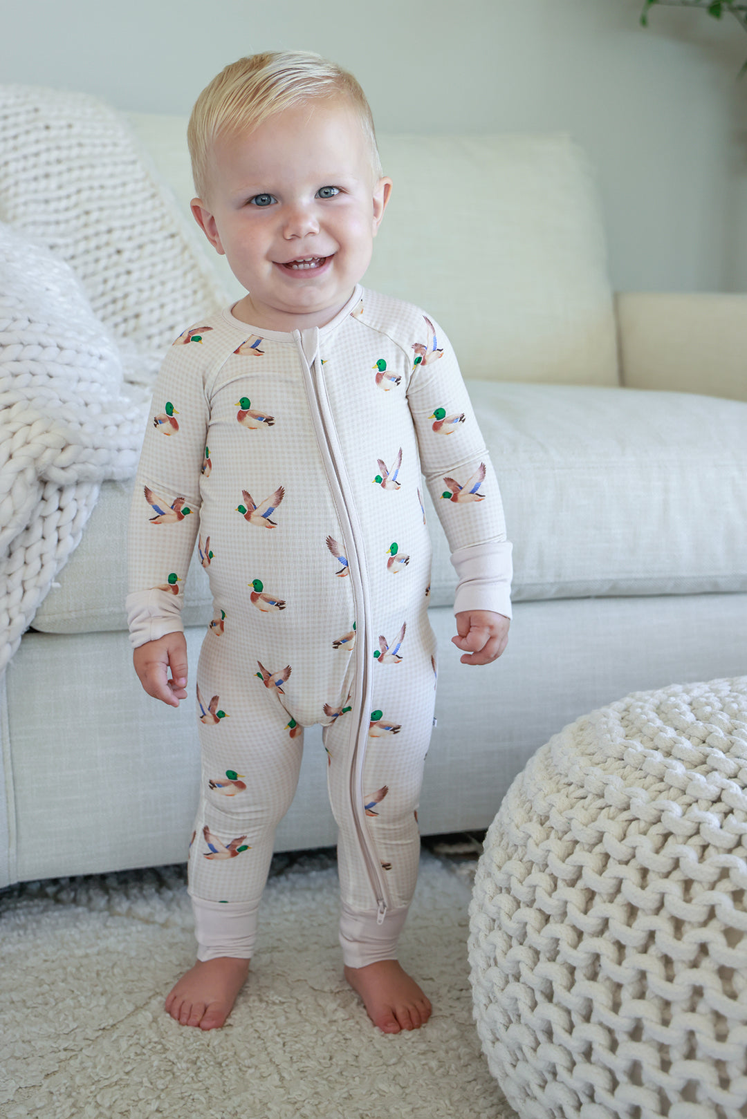 Smiling toddler standing in little mallard duck print convertible zip romper showing full front length view