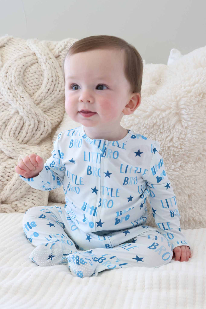 baby boy sitting on bed in little bro star zipper footie pajama 