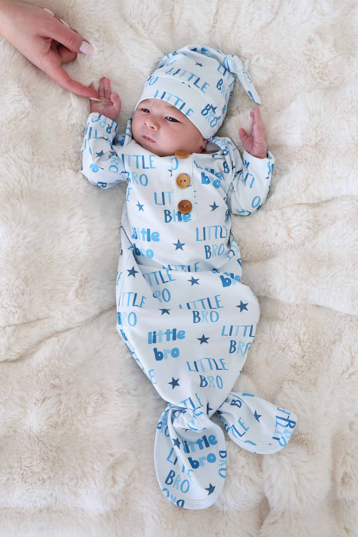 baby boy wearing the little bro newborn knot gown and hat set holding mom's finger