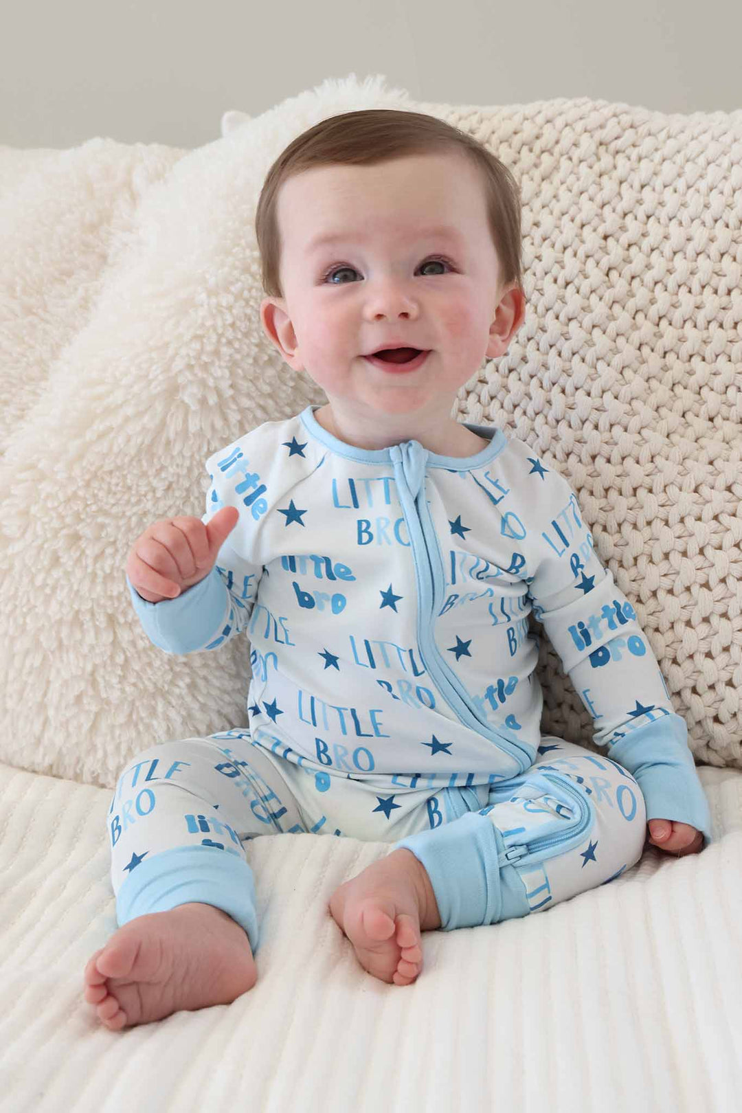 boy sitting on bed in blue star little bro convertible zip romper 