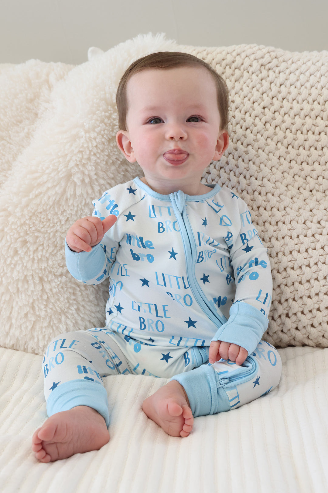 boy sticking out his tongue wearing the little bro star convertible zip romper in blue 