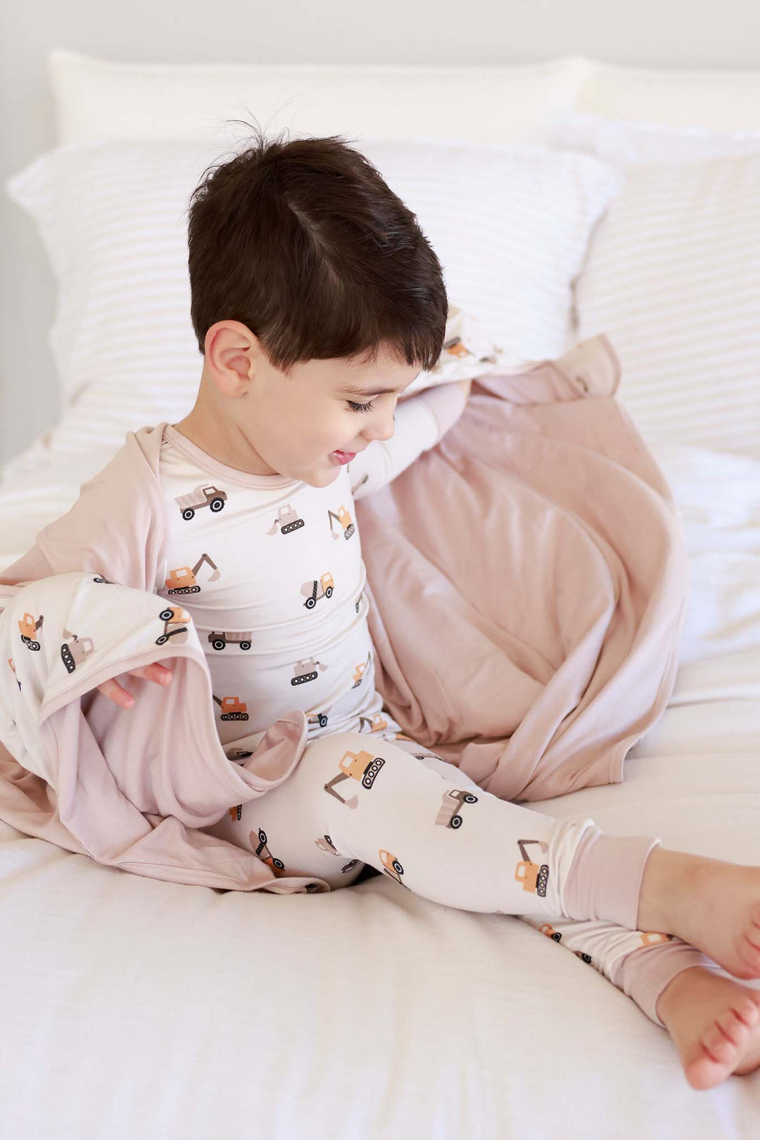 bow sitting with ankles crossed with  neutral construction bamboo blanket wrapped around him