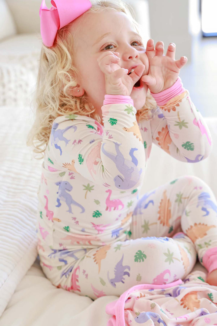 little girl wearing pastel dinosaur pajamas and roaring 