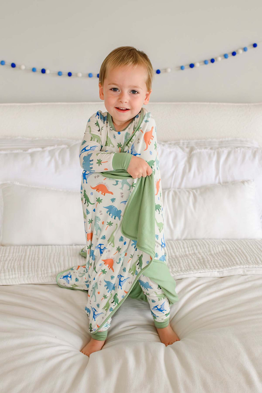 boy wearing the little fossil pajama set with  matching blanket wrapped around him