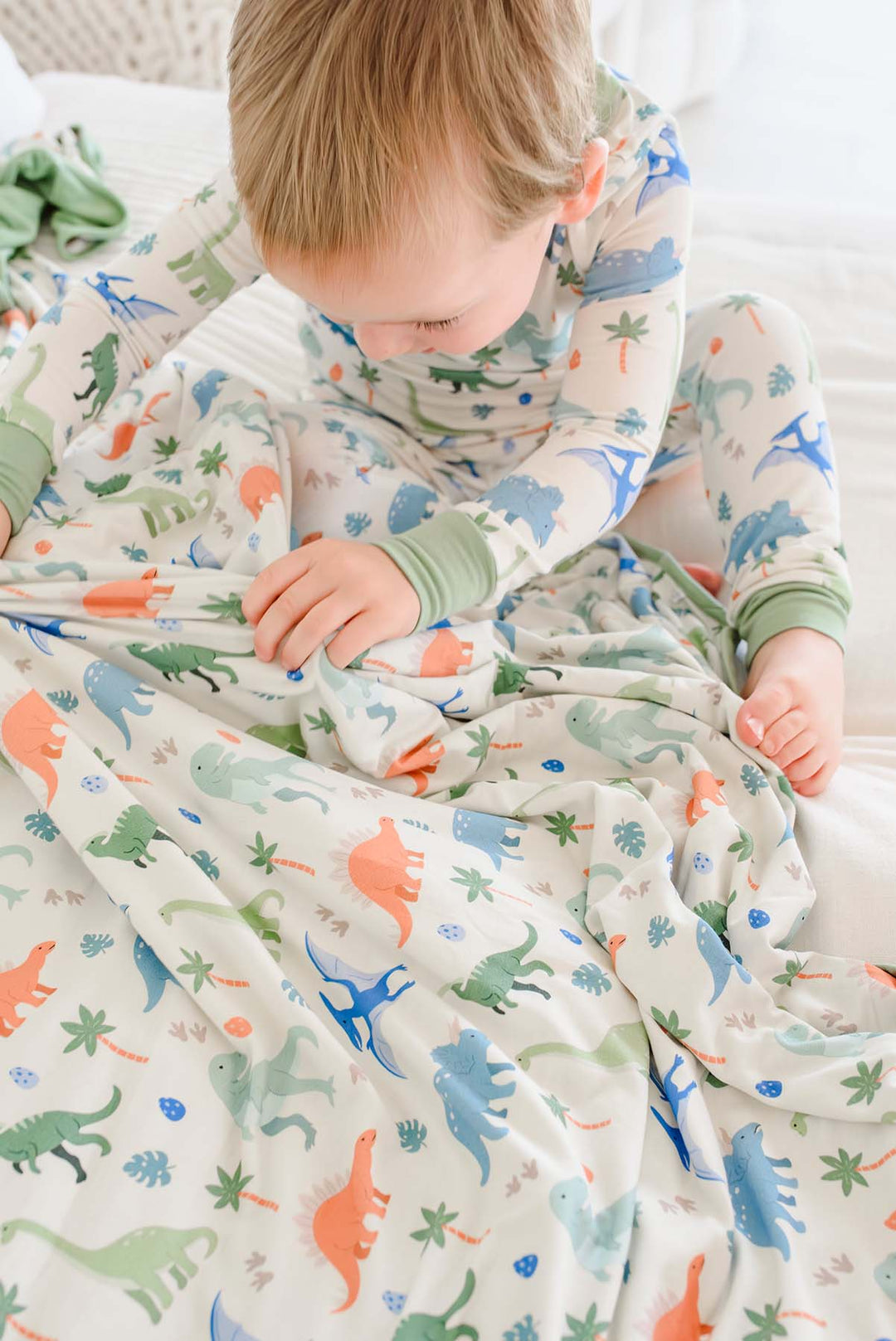 blue, orange and green dinosaur long sleeve shirt and pant pajama set with a matching bamboo blanket