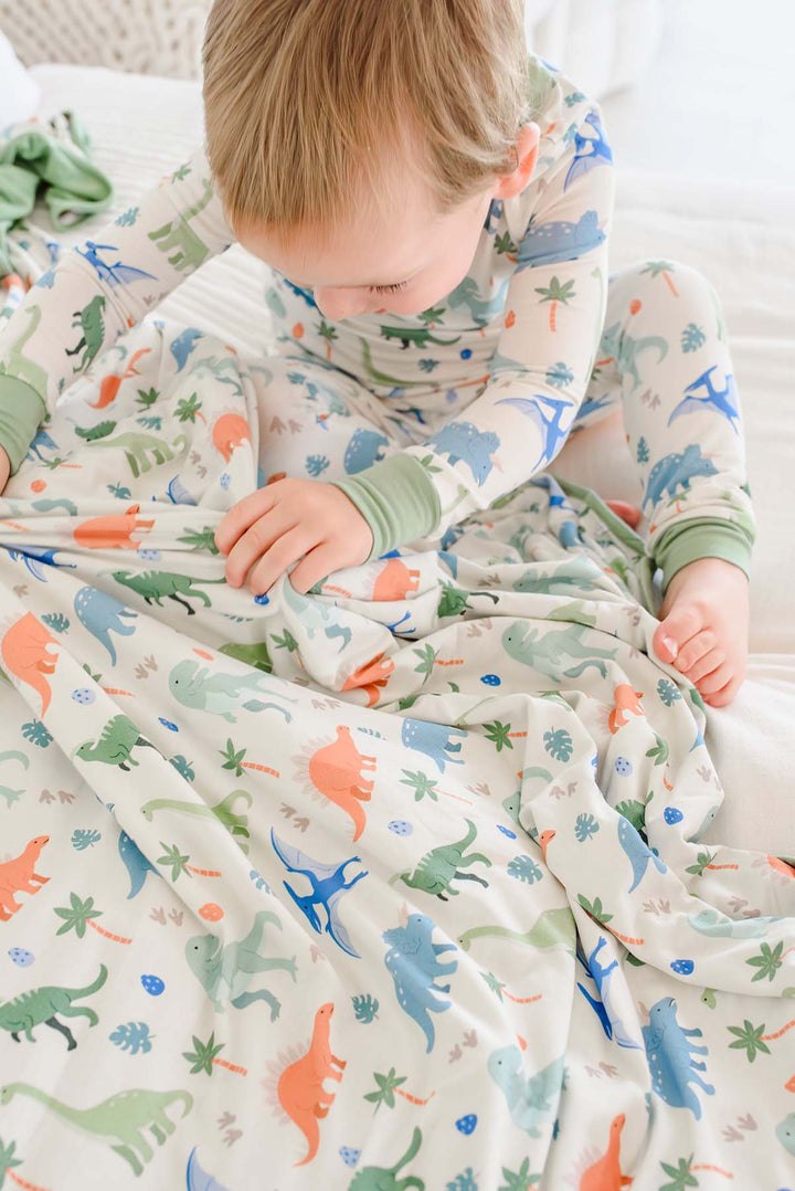 blue, orange and green dinosaur long sleeve shirt and pant pajama set with a matching bamboo blanket