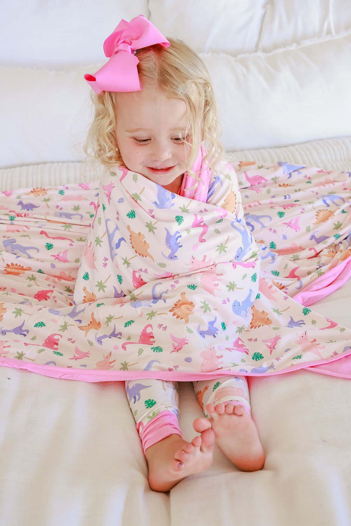 girl wrapped in pastel dinosaur blanket