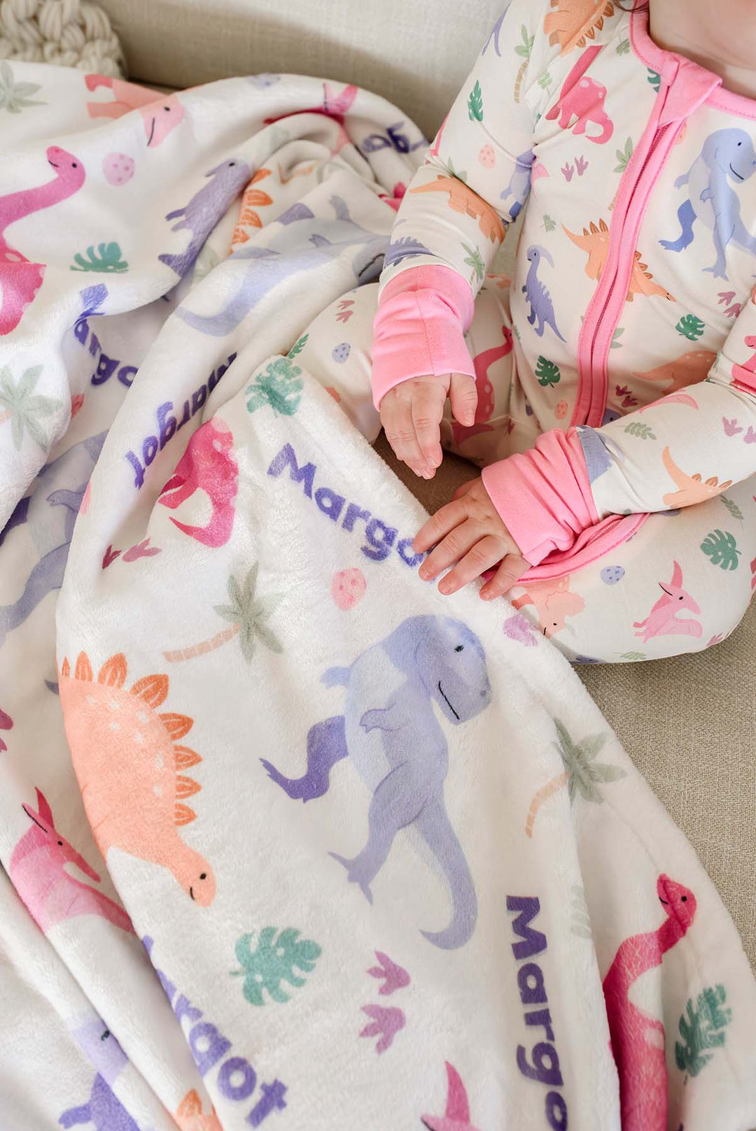 closeup of little fossil pink personalized blanket for girls with matching convertible zip rompers