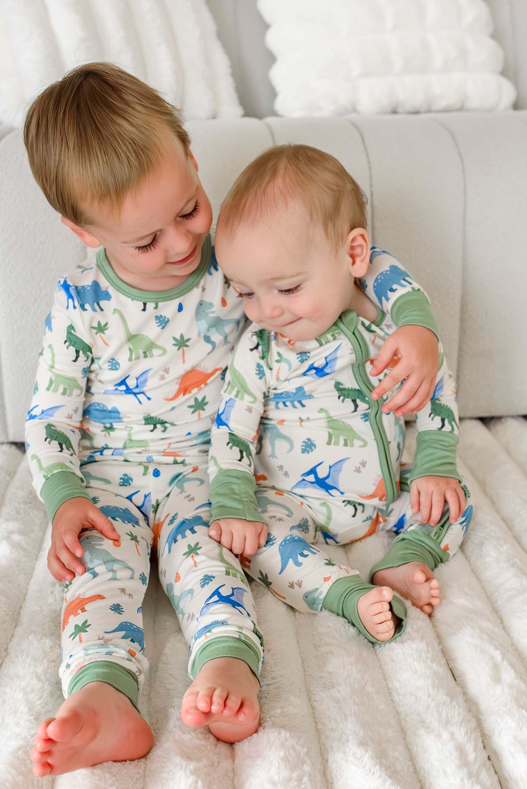 big brother with arm around little brother wearing little fossil neutral pajamas