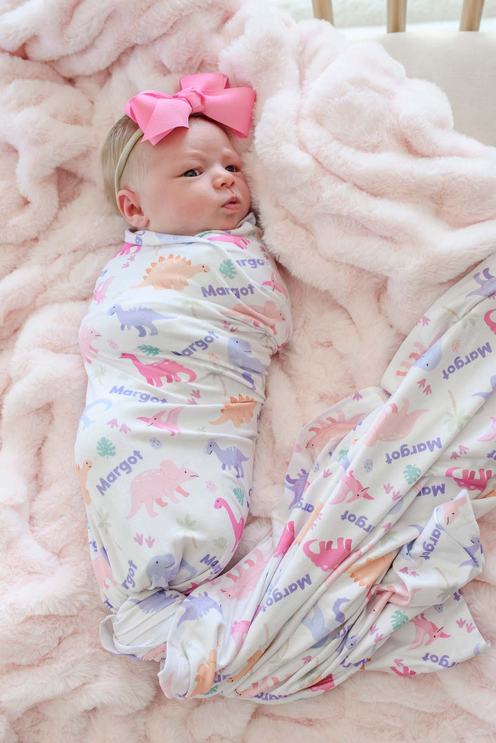 baby girl swaddle blanket with pastel dinosaurs with pink ribbon bow headband 