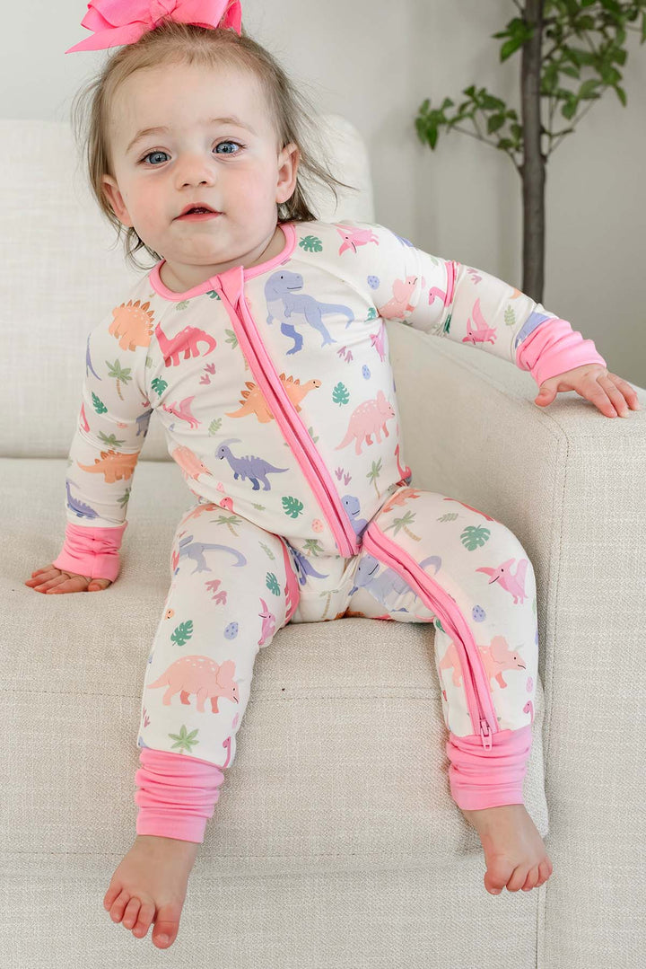 toddler girl sitting on chair in pink little fossil convertible zip romper with matching ribbon clip bow